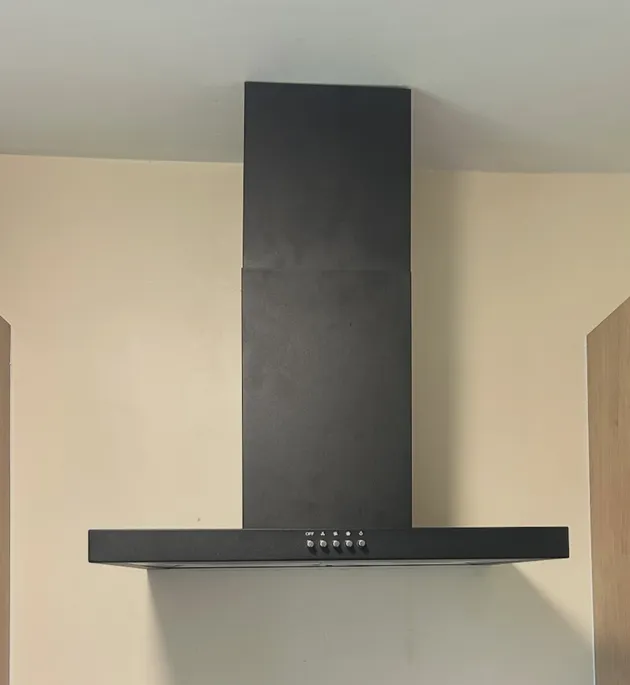 Black wall-mounted range hood installed in a kitchen